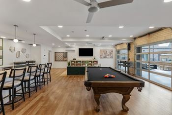 A room with a pool table and chairs.